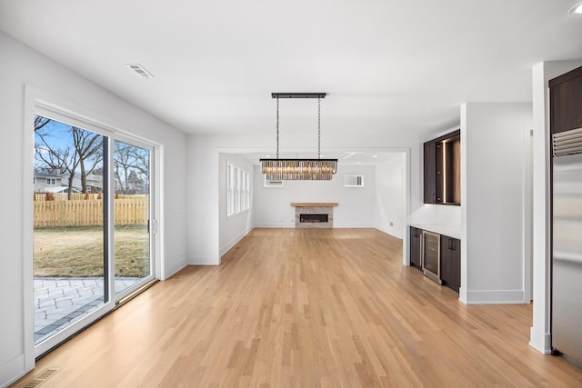 unfurnished living room featuring light wood-style flooring, a fireplace, visible vents, and baseboards