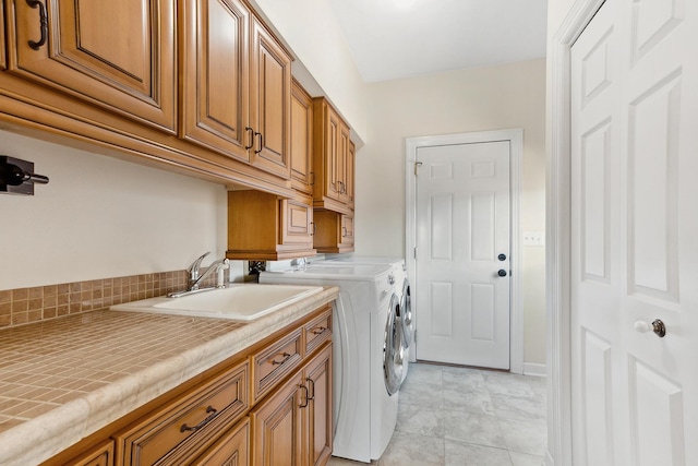 laundry room featuring light tile patterned flooring, cabinet space, independent washer and dryer, and a sink