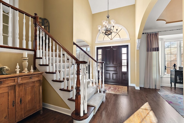 entrance foyer featuring a towering ceiling, stairs, baseboards, and dark wood-style flooring