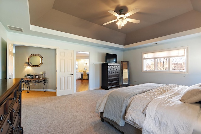 bedroom with visible vents, baseboards, light colored carpet, lofted ceiling, and a tray ceiling