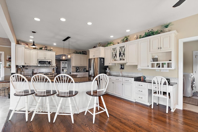 kitchen with washer and dryer, dark countertops, a breakfast bar area, and stainless steel appliances