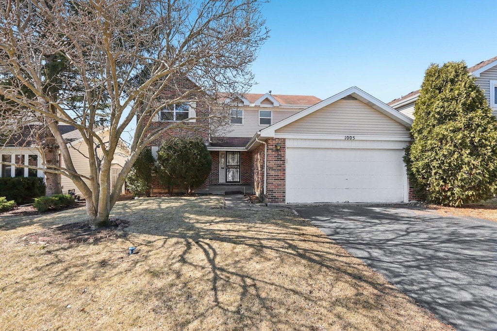 view of front facade with a garage, brick siding, and driveway