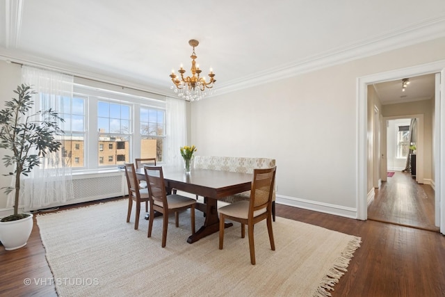 dining space with radiator, crown molding, an inviting chandelier, and wood finished floors