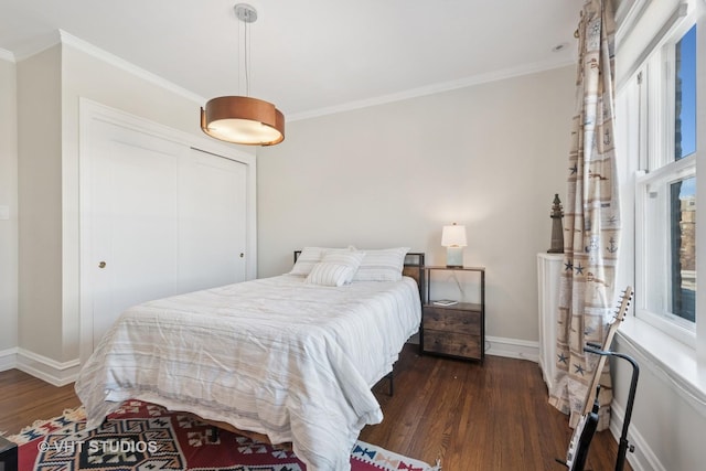 bedroom featuring a closet, baseboards, dark wood finished floors, and ornamental molding