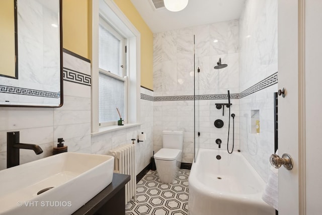 bathroom featuring radiator, a sink, bathtub / shower combination, tile walls, and toilet