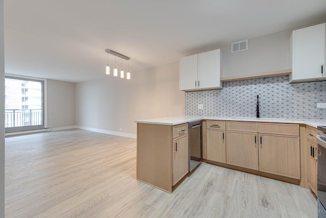 kitchen featuring dishwasher, a peninsula, backsplash, and a sink