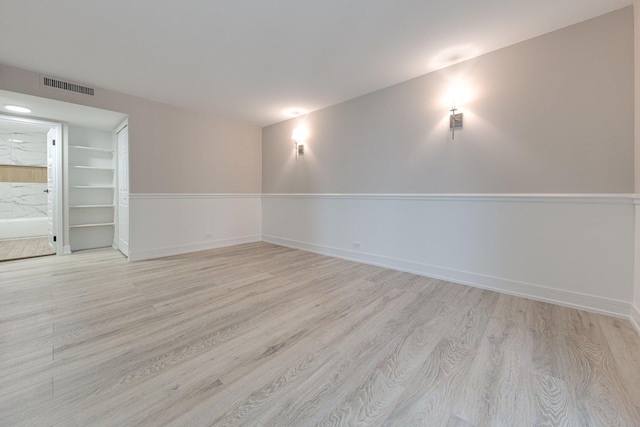 unfurnished room featuring visible vents, baseboards, and wood finished floors