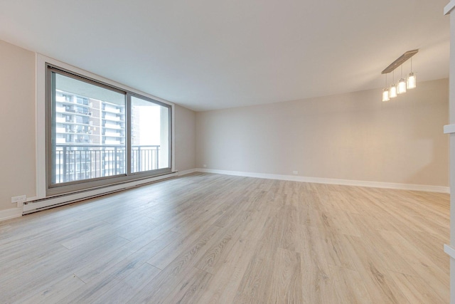 spare room featuring light wood finished floors, baseboards, and a baseboard heating unit