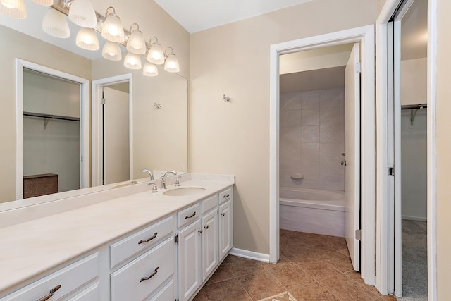 bathroom featuring tile patterned floors, vanity, baseboards, and a spacious closet