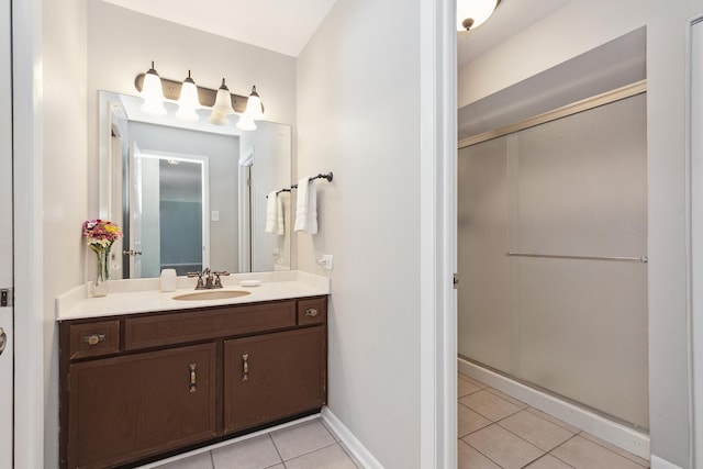 full bathroom with a stall shower, vanity, baseboards, and tile patterned floors