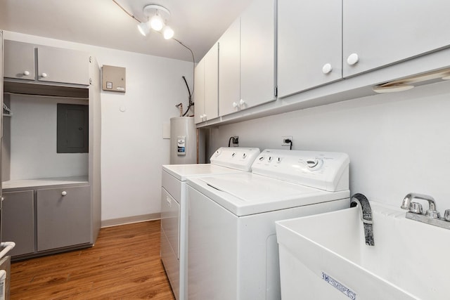 laundry area with cabinet space, electric panel, electric water heater, washing machine and dryer, and a sink