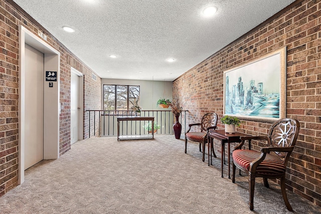 living area featuring a textured ceiling, recessed lighting, brick wall, carpet, and elevator