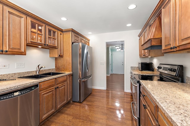 kitchen with brown cabinets, appliances with stainless steel finishes, dark wood finished floors, and a sink