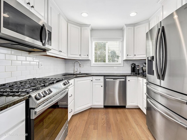 kitchen featuring white cabinets, light wood finished floors, appliances with stainless steel finishes, and a sink