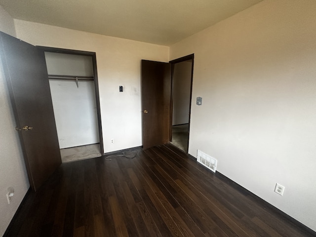 unfurnished bedroom featuring a closet, visible vents, and wood finished floors