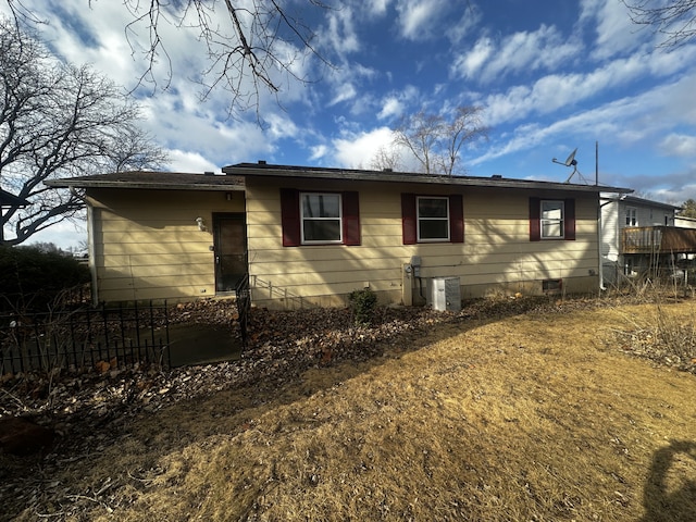 view of side of home with cooling unit, crawl space, and fence