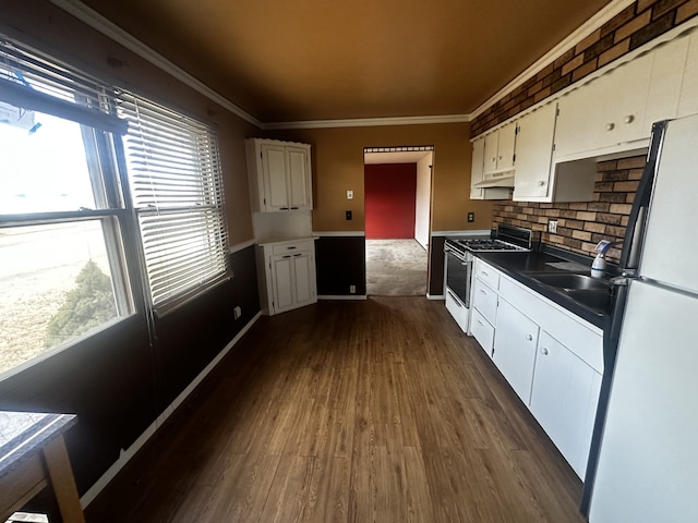 kitchen with freestanding refrigerator, range with gas cooktop, white cabinets, and crown molding