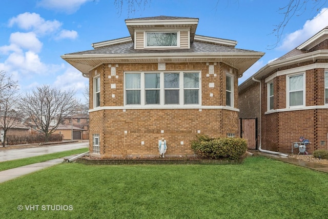 view of front of house featuring a front lawn, brick siding, and roof with shingles