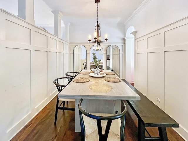 dining space with ornamental molding, dark wood-style flooring, ornate columns, a chandelier, and a decorative wall