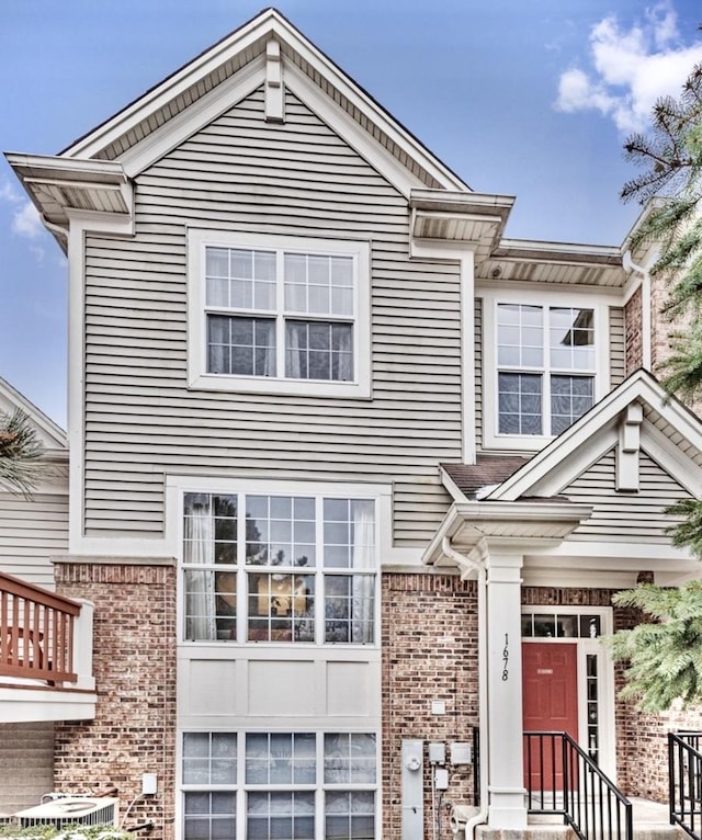 view of front of property with central AC and brick siding