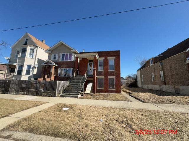 tri-level home with a fenced front yard, brick siding, and stairs