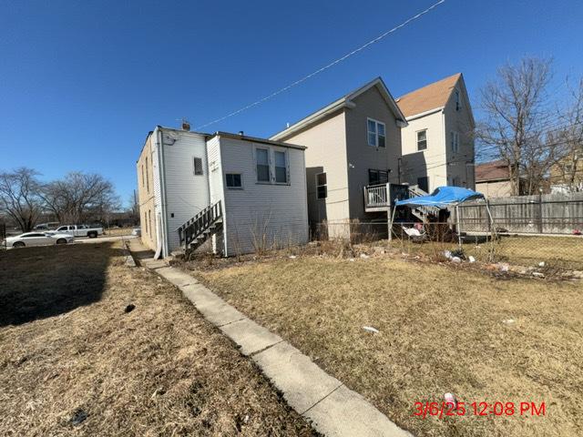 exterior space with entry steps, fence, and a lawn