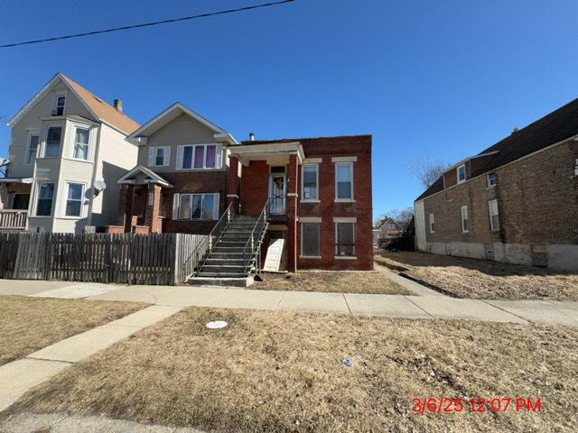 view of front of property with a fenced front yard, stairway, and brick siding