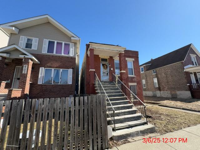 view of front facade with brick siding and fence