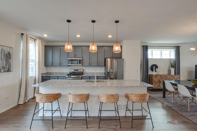 kitchen with a center island with sink, appliances with stainless steel finishes, a kitchen bar, and a sink