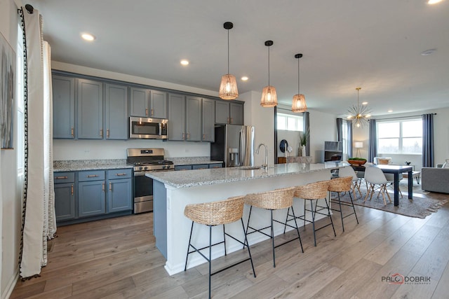 kitchen with a kitchen bar, a large island, light wood-type flooring, and stainless steel appliances