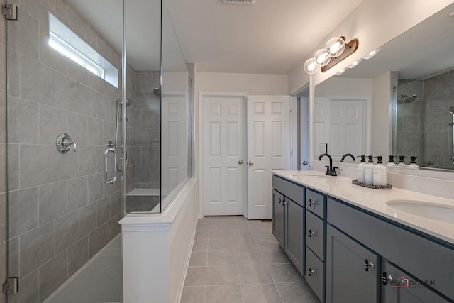 full bathroom featuring tile patterned floors, tiled shower, and a sink