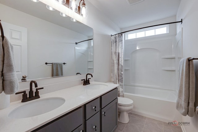 bathroom with tile patterned floors, double vanity, toilet, and a sink