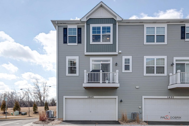 back of property with a balcony, board and batten siding, and central AC