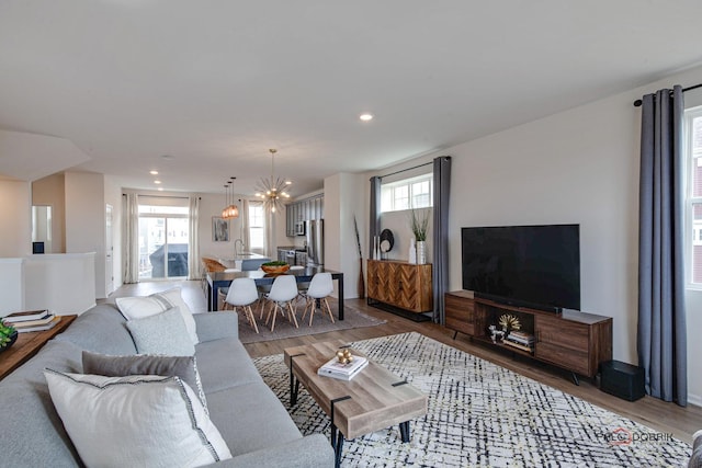 living room featuring a notable chandelier, recessed lighting, and light wood finished floors