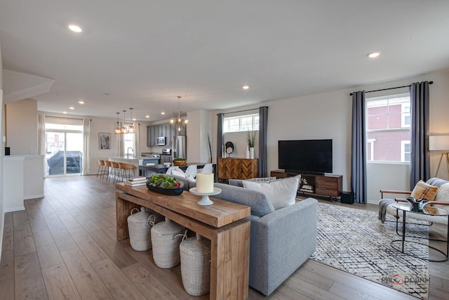 living room featuring a chandelier, recessed lighting, light wood-style flooring, and baseboards