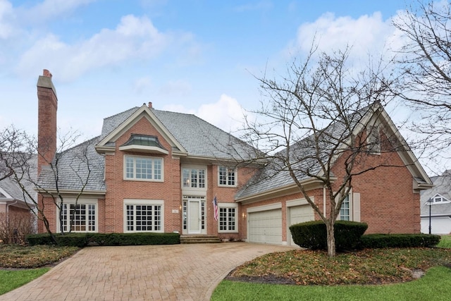 colonial inspired home featuring brick siding, driveway, and a garage