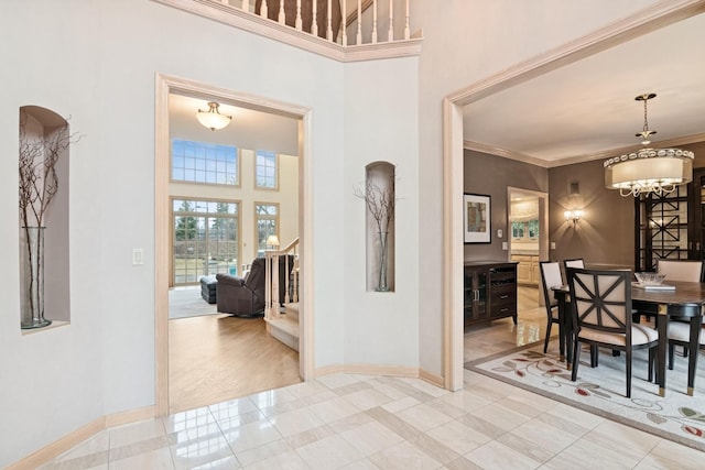 dining space featuring stairway, a high ceiling, crown molding, and baseboards