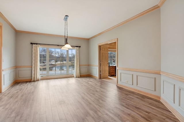 unfurnished room featuring light wood-type flooring, a wainscoted wall, and ornamental molding