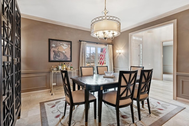 dining room featuring a decorative wall, wainscoting, crown molding, and an inviting chandelier