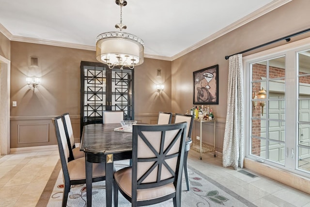 dining area with visible vents, a wainscoted wall, crown molding, and a decorative wall