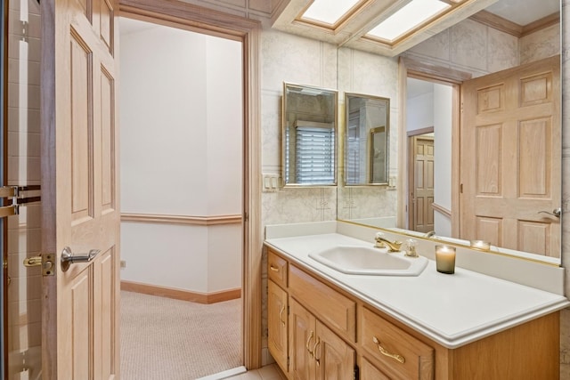 bathroom with vanity, a skylight, and baseboards