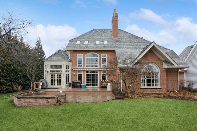 back of property featuring french doors, brick siding, a yard, and a chimney