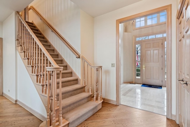 foyer entrance featuring stairway, a high ceiling, baseboards, and wood finished floors