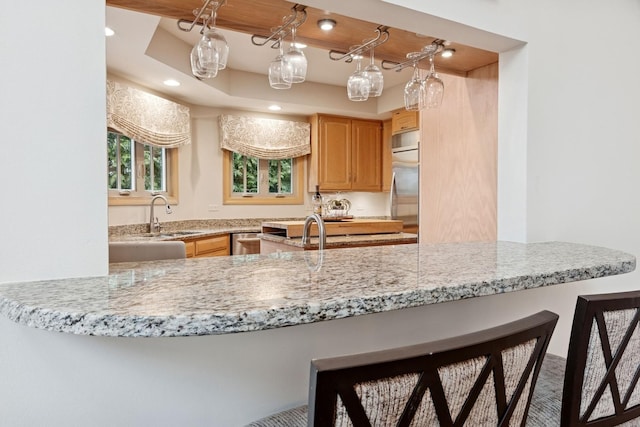 kitchen featuring a sink, a tray ceiling, recessed lighting, appliances with stainless steel finishes, and a breakfast bar area