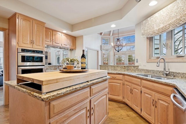 kitchen with a sink, light brown cabinetry, stainless steel appliances, light wood-style floors, and a wealth of natural light