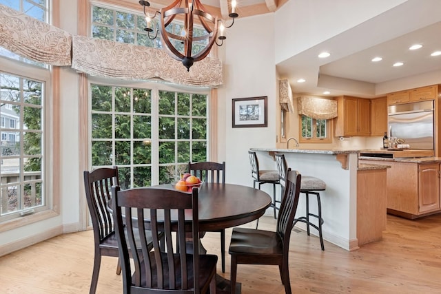 dining room featuring a notable chandelier, light wood-style flooring, recessed lighting, a high ceiling, and baseboards