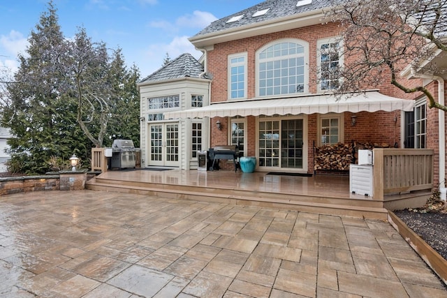 rear view of house with french doors, a patio, brick siding, and a wooden deck