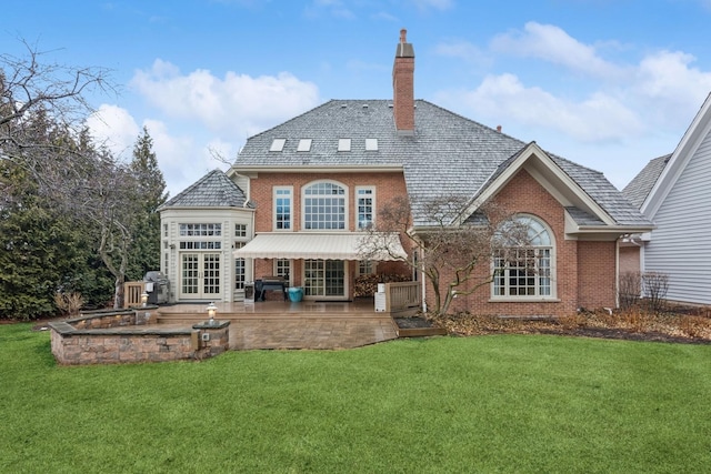 back of house featuring brick siding, a lawn, french doors, and a chimney