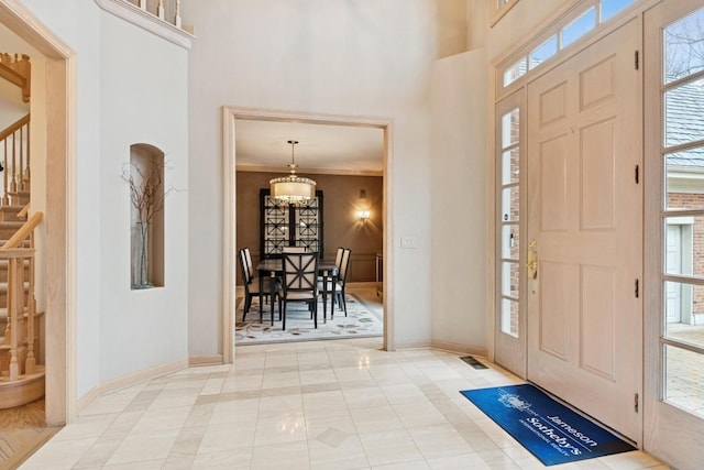 foyer entrance with an inviting chandelier, stairway, a healthy amount of sunlight, and baseboards