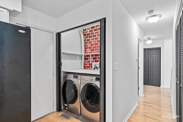 washroom with light wood-type flooring, baseboards, laundry area, and washer and clothes dryer